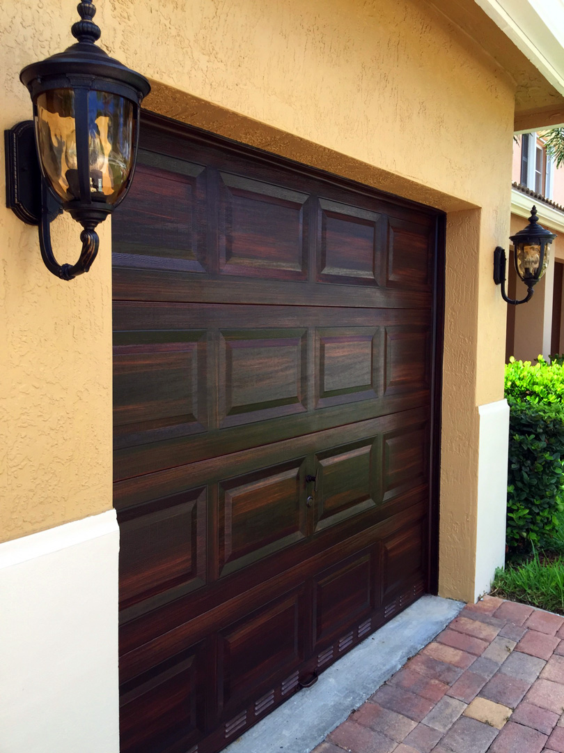 Faux mahogany finish on single garage door with elegant lighting